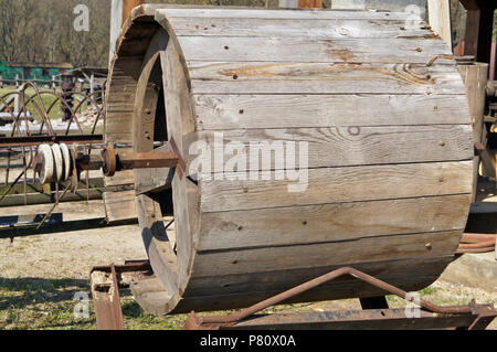 Eine große hölzerne Trommel für landwirtschaftliche Maschinen liegt in der Nähe des Dorfes Scheune installiert. Sonniger Frühlingstag Außenaufnahme Stockfoto