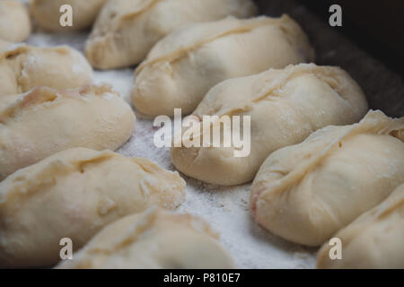 Gefüllte vareniki oder Knödel auf braun Platine mit Mehl bestäubt. Sie können gefüllt mit Kirschen, Kartoffeln und Kohl. Dies ist eine traditionelle ukrainische Ein Stockfoto