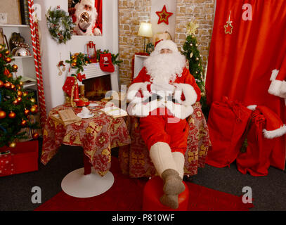 Santa Claus Nickerchen auf dem Sessel zu Hause im Wohnzimmer Stockfoto