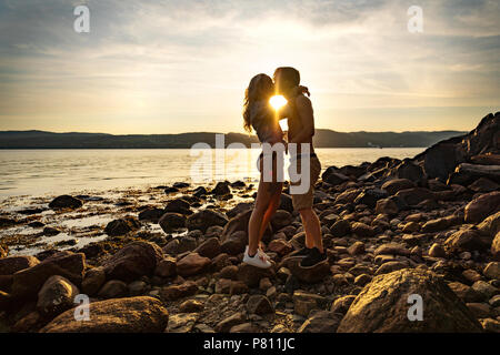 Silhouette von Paar in Liebe umarmen am Strand gegen Sonne Stockfoto