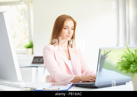 Portrait von schönen jungen Geschäftsfrau, sitzen im modernen Büro- und Arbeiten am Laptop. Stockfoto