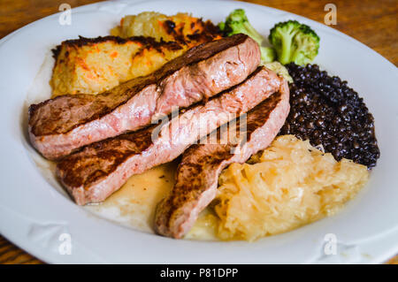 Einfache deutsche Gericht zum Mittagessen aus Schweinefleisch steak Slices, Sauerkraut, schorles und Beluga Salat mit Linsen Stockfoto