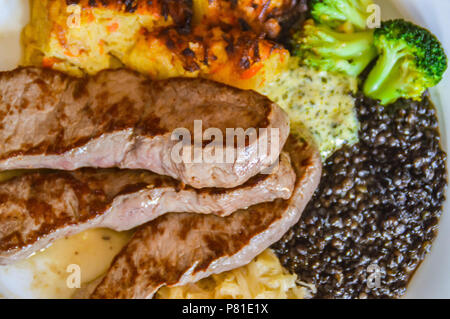 Einfache deutsche Gericht zum Mittagessen aus Schweinefleisch steak Slices, Sauerkraut, schorles und Beluga Salat mit Linsen Stockfoto