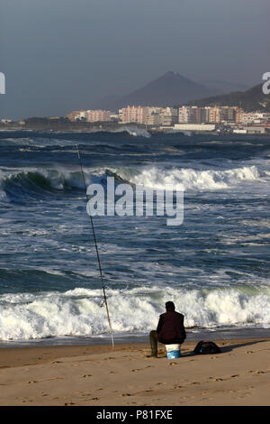 Mann Seefischen vom Sandstrand, Vila Praia de Ancora und Cerro Santa Tecla / Santa Trega (Spanien) im Hintergrund, Minho Provinz, Nordportugal Stockfoto