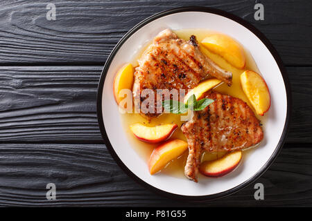 Schweinefleisch vom Grill mit glasierten Pfirsichen und Honig Knoblauch Sauce schließen chop - bis auf einen Teller auf dem Tisch. horizontal oben Ansicht von oben Stockfoto