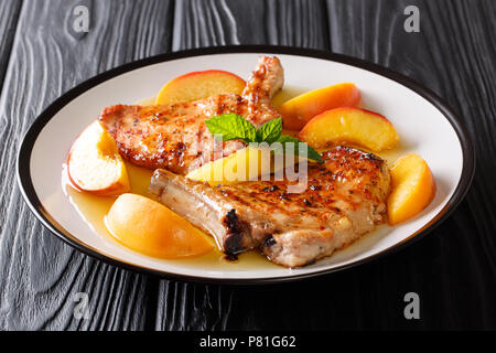 Französische Rezept gegrillte Pikante Schweinefleisch mit Pfirsichen, Honig Knoblauch Sauce und Minze closeup auf einem Teller. Horizontale Stockfoto