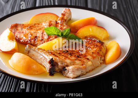 Gegrillte pikanter Schweinefilet mit Pfirsichen, Honig Knoblauch Sauce und Minze closeup auf einem Teller. Horizontale Stockfoto