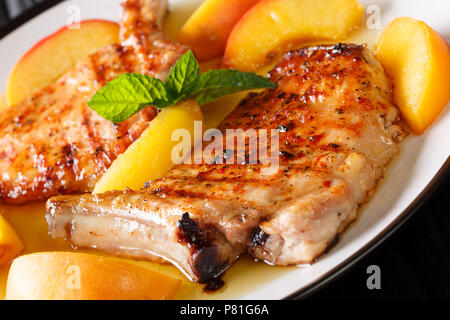 Lecker gegrilltes Schweinefleisch mit frischen Pfirsichen und Honig Knoblauch Sauce close-up auf einem Teller hacken. Horizontale Stockfoto