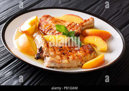 Hot gegrillten würzigen Schweinefleisch mit glasierten frische Pfirsiche und Minze closeup auf einem Teller. Horizontale Stockfoto