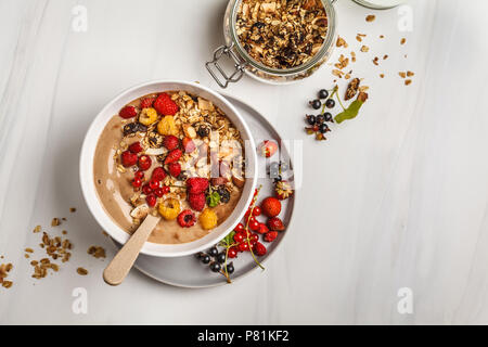 Smoothie Schüssel mit Bananen, Kakao, Beeren und hausgemachtem Müsli. Veganes Frühstück Banane Eiscreme. Gesunde vegane Ernährung Konzept. Stockfoto