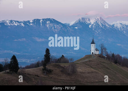 Kirche St. Primoz in der Dämmerung in der Nähe von Jamnik, vor der dramatischen Kulisse des Mount Storzic, Gorenjska, Slowenien, Europa Stockfoto