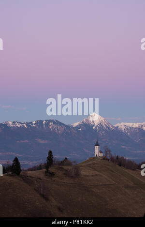 Kirche St. Primoz in der Dämmerung in der Nähe von Jamnik, vor der dramatischen Kulisse des Mount Storzic, Gorenjska, Slowenien, Europa Stockfoto