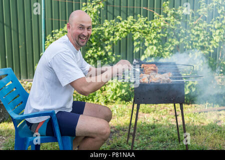 Schöner mann Vorbereitung Grill für Freunde. Junges Paar, Grill im Garten Stockfoto