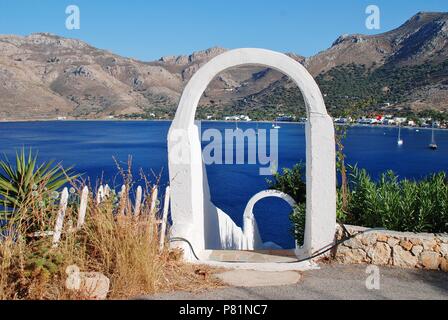 Einen weißen Torbogen frames Livadia Hafen auf der griechischen Insel Tilos am 12. Juni 2018. Stockfoto