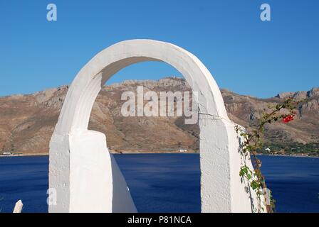 Einen weißen Torbogen frames Livadia Hafen auf der griechischen Insel Tilos am 12. Juni 2018. Stockfoto