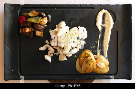 Gehackte Tintenfisch auf einem Teller mit Gemüse, Kartoffeln und Soße rosated Stockfoto