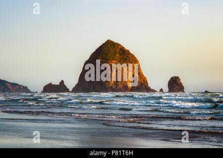 Die Haystack Rock bei Flut und bei Sonnenuntergang. Berühmte und legendäre Meer in Cannon Beach, Oregon, USA Stack entfernt. Stockfoto