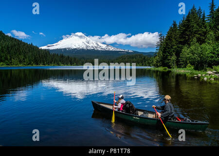 Vater, Tochter mit ihrem Hund Kanu fahren auf Trillium See an einem schönen sonnigen Tag des Sommers mit Mt. Haube auf dem Wasser widerspiegeln, Oregon, USA. Stockfoto