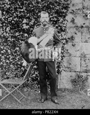 Englisch: Foto von Nikolaus II., Kaiser von Rußland, außerhalb Balmoral. Er trägt eine britische Uniform und hält eine Bärenfellmütze hat in seiner rechten Hand ein Schwert und in der linken. Es ist eine Mauer teilweise mit Efeu hinter ihm und ein Stuhl auf der linken Seite. 1896 Nikolaus II., seiner Gemahlin Alexandra Feodorowna und seine älteste Tochter Großfürstin Olga Nikolajewna besuchte Königin Victoria im Balmoral. Alexandra Feodorovna war eine Enkelin der Queen. 1896 287 Nikolaus II., Kaiser von Russland Stockfoto