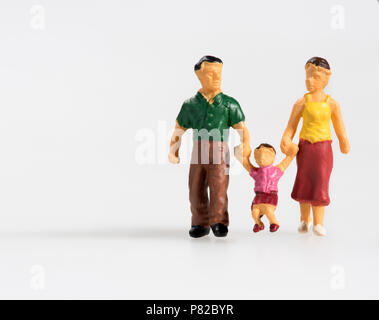 Glückliche Familie mit kleinem Kind miniatur Spielzeug Leute mit den Eltern und ihrem Sohn Holding durch die Hand zwischen ihnen auf Weiß mit Co isoliert Stockfoto
