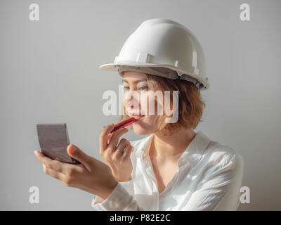 Schöne asiatische Frau Ingenieur curly kurze Haare tragen weiße Helm und weißem T-Shirt Make-up mit rotem Lippenstift, berufstätige Frau Konzept. Stockfoto
