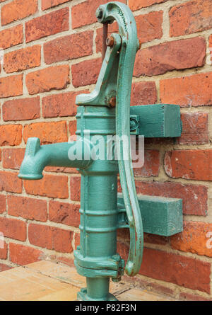 Alte hand Wasser pumpe gegen die Wand montiert Stockfotografie