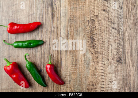 Fünf rote und grüne Chili auf hölzernen Tisch Stockfoto