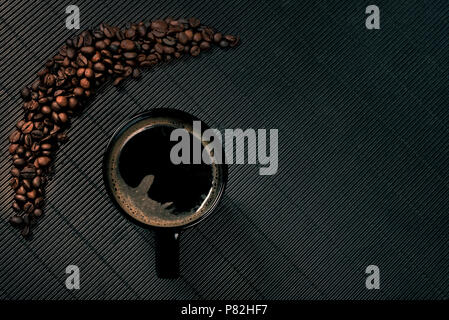Schwarzer Kaffeebecher in der Nähe von Kaffeebohnen auf Moody Hintergrund Stockfoto