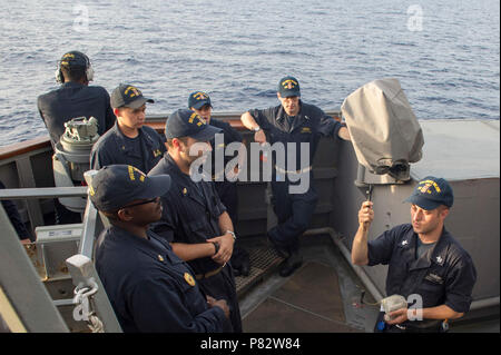 CHINA SEA (4. Juli 2016) - der Gunner Mate 1. Klasse Joseph Sexton zeigt das richtige Verfahren zum Halten einer Bleistift flare während des Trainings auf dem Port bridge-Flügel der Arleigh-Burke-Klasse geführte Anti-raketen-Zerstörer USS Curtis Wilbur (DDG54). Curtis Wilbur ist auf Patrouille mit Carrier Strike Group (CSG) 5 in den USA 7 Flotte der Verantwortung für Sicherheit und Stabilität in der Indo-Asia - Pazifik. Stockfoto