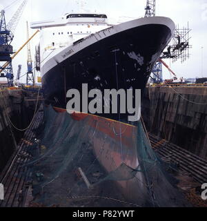 AJAXNETPHOTO. Dez 1996. SOUTHAMPTON, England. - BOW VIEW DER CUNARD PASSAGIERSCHIFF QUEEN ELIZABETH 2-QE 2-IN KGV-DRY DOCK, ihrem Rumpf eingehüllt in Netting, erfährt wieder einbauen. Foto: Jonathan Eastland/AJAX. REF: 1296 31 Stockfoto