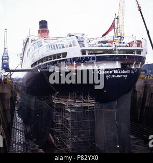 AJAXNETPHOTO. Dez 1996. SOUTHAMPTON, England. - Hafen VIERTEL ANSICHT DER CUNARD PASSAGIERSCHIFF QUEEN ELIZABETH 2-QE 2-IN KGV-DRY DOCK, ihrem Rumpf eingehüllt in Netting, erfährt wieder einbauen. Foto: Jonathan Eastland/AJAX. REF: 1296 34 Stockfoto