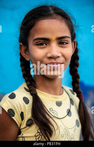 JODHPUR, Rajasthan - Indien - 12. Dezember 2017. Porträt einer wunderschönen und lächelnd Indisches Kind mit ihrem Haar zu Zöpfen gesammelt und einem blauen backgroun Stockfoto