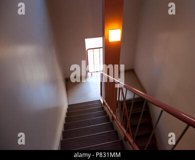 Eine Treppe in einem rosa Flur mit einem Geländer für die Sicherheit Stockfoto