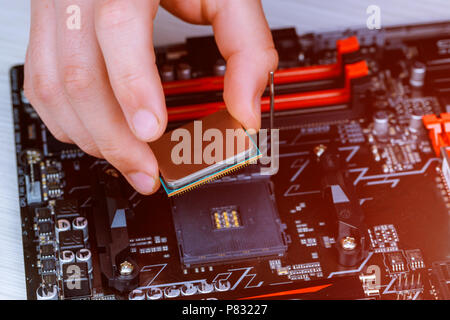 Der Techniker setzt die CPU auf dem Sockel der Computerhauptplatine. Das Konzept der Computer Hardware, Reparatur, Upgrade und Technologie. Stockfoto