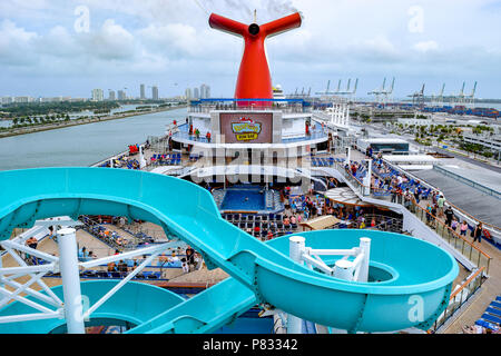 Miami, Florida - 29. März 2014: die Passagiere an Bord der Carnival Liberty Kreuzfahrt in Miami, oben offenen Decks mit Wasserrutsche im Vordergrund. Stockfoto