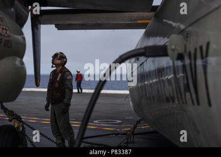 Pazifik (Nov. 28, 2016) Petty Officer 2nd class Winer Fung, aus Oakland, Kalifornien, führt eine Drehung um die Überprüfung auf der C-2A Greyhound von den Anbietern des Fleet Logistics Combat Support Squadron (VRC) 30, Distanz 4, auf USS John C Stennis" (CVN 74) Flight Deck Mission die Bereitschaft der Flugzeuge zu gewährleisten. John C Stennis ist unterwegs Routine Training zu leiten und in nationalen Pearl Harbor Erinnerung Tag der Ereignisse in Hawaii teilnehmen. Stockfoto