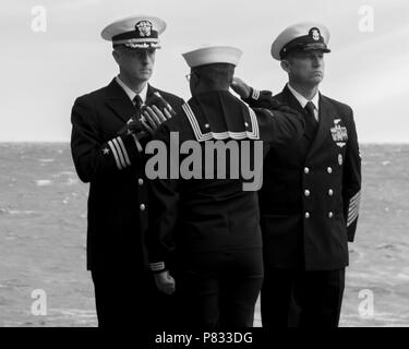 Atlantik (31. 3, 2016) Petty Officer 3rd class Joey Rush, aus Detroit, grüßt, Cmdr. Colin Tag, Executive Officer der Flugzeugträger USS George Washington (CVN 73), während einer Bestattung auf See Zeremonie. George Washington, homeported in Norfolk unterwegs ist die Durchführung von Carrier Qualifikationen in den Atlantischen Ozean. Stockfoto