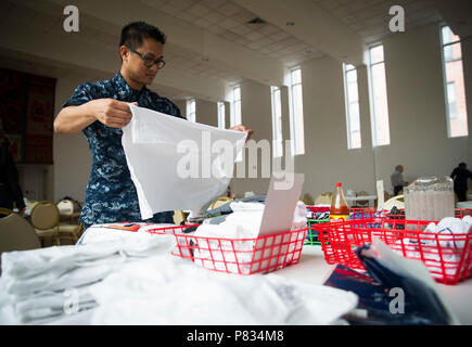 NORFOLK (Feb. 27, 2017) Hospital Corpsman 2. Klasse Diosdado Valera, aus San Diego, und auf dem Flugzeugträger USS George Washington (CVN 73) Falten spendete t-shirts während eines freiwilligen Bemühung an der Ohef Sholom Tempel Suppenküche zugeordnet. Segler zugewiesen wurde George Washington, der Amphibisches Schiff USS Wasp (LHD 1) und Angriff Craft Unit (ACU) 2 von Naval Beach Group (NBG) 2 Verband Mitglieder der Ohef Sholom Tempel in der Zubereitung und Verteilung der gespendeten Waren, die in der Notwendigkeit während der monatsbericht der Tempel Armenküche in Norfolk. Stockfoto