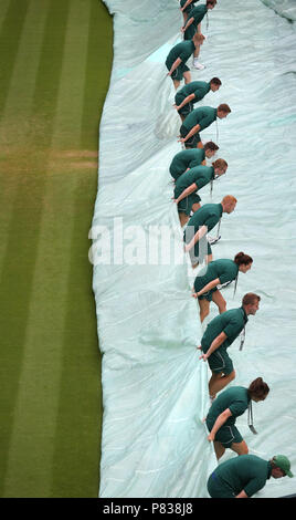 Das bodenpersonal über Nacht Abdeckungen entfernen aus den Gerichten am Tag sieben der Wimbledon Championships in der All England Lawn Tennis und Croquet Club, Wimbledon. Stockfoto