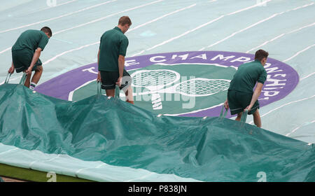 Das bodenpersonal über Nacht Abdeckungen entfernen aus den Gerichten am Tag sieben der Wimbledon Championships in der All England Lawn Tennis und Croquet Club, Wimbledon. Stockfoto