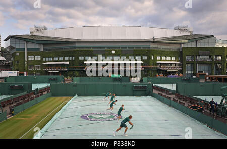 Das bodenpersonal über Nacht Abdeckungen entfernen aus den Gerichten am Tag sieben der Wimbledon Championships in der All England Lawn Tennis und Croquet Club, Wimbledon. Stockfoto