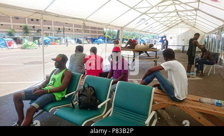 Rom, Italien. 04. Juli 2018. Migranten sitzen auf Stühlen und Bänken unter einem großen Zelt in einem Camp im Roma Tiburtina Bahnhof. Credit: Gabriele Hafner/dpa/Alamy leben Nachrichten Stockfoto