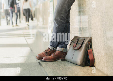 Männer tragen Jeans und Leder Taschen auf der Straße Flure. Stockfoto