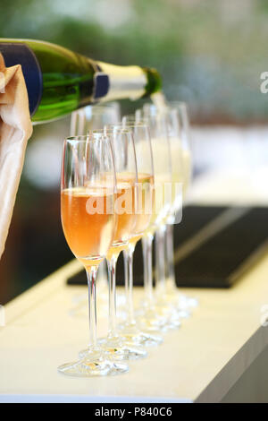 In Gläser gießen Prosecco in Reihe stehen Stockfoto