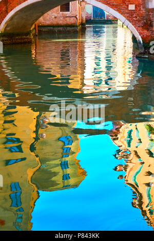 Venezianischer Spiegel - Häuser, blauer Himmel und die kleine Brücke im Wasser des Kanals widerspiegeln. Venedig im Wasser Reflexionen Stockfoto