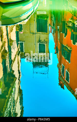 Venezianischer Spiegel - Häuser, Boot und blauer Himmel im Wasser des Kanals widerspiegeln. Venedig im Wasser Reflexionen Stockfoto