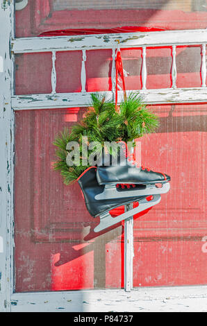 Paar schwarze Schlittschuhe mit roten Ösen und Schnürsenkel gefüllt mit Evergreens - sehr festlich Stockfoto