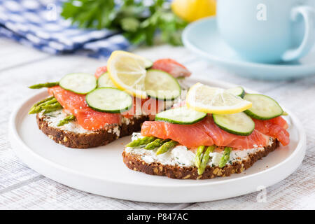 Lachs Sandwiches mit Spargel, Frischkäse und Gurke auf weiße Platte. Gesundes Frühstück oder gesunden Snack. Selektiver Fokus Stockfoto