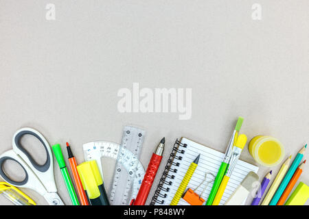 Vielzahl von Schulmaterial mit Bleistiften, Notebook, Markierungen auf grauem Hintergrund. Flache Ansicht Stockfoto