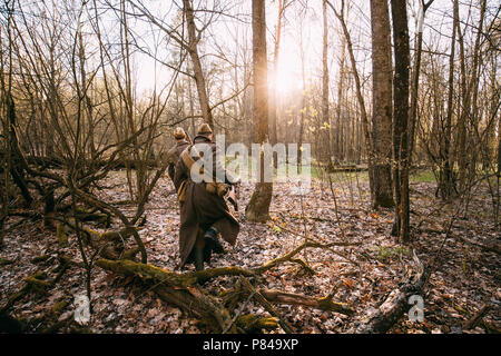 Zwei Re-enactors Als russische Sowjetische Infanterie Rote Armee Soldaten des Zweiten Weltkriegs zu Fuß mit der Waffe Gewehre im Herbst Wald gekleidet. Stockfoto